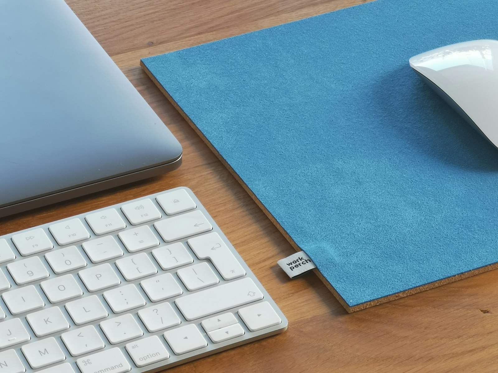 A vibrant blue desk mat with a mouse on a wooden desk.