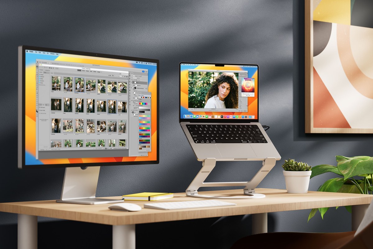 Photo of a MacBook elevated on the white Twelve South Curve Flex laptop stand on a desk, next to an external monitor.